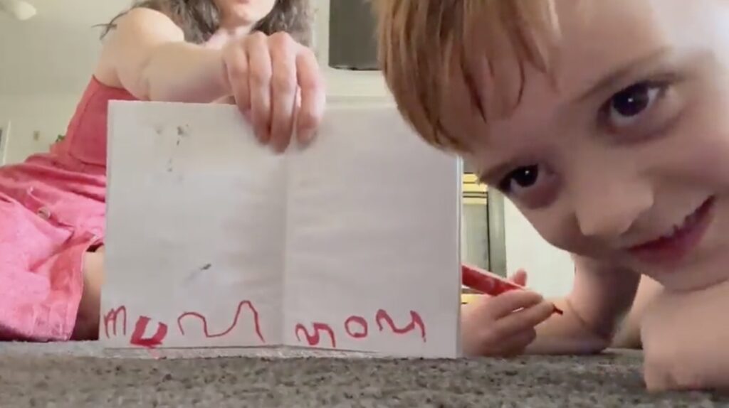 Young child showing his new literacy and writing skills to his Mom