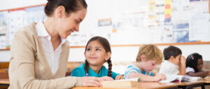 Smiling teacher with students using the science of reading to learn literacy skills